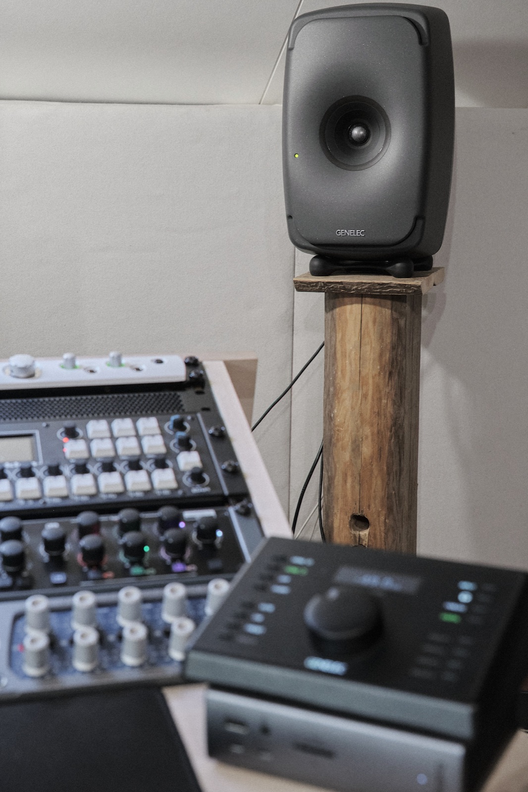 Genelec monitor speaker on a wooden post, with monitor controller and rack in the foreground